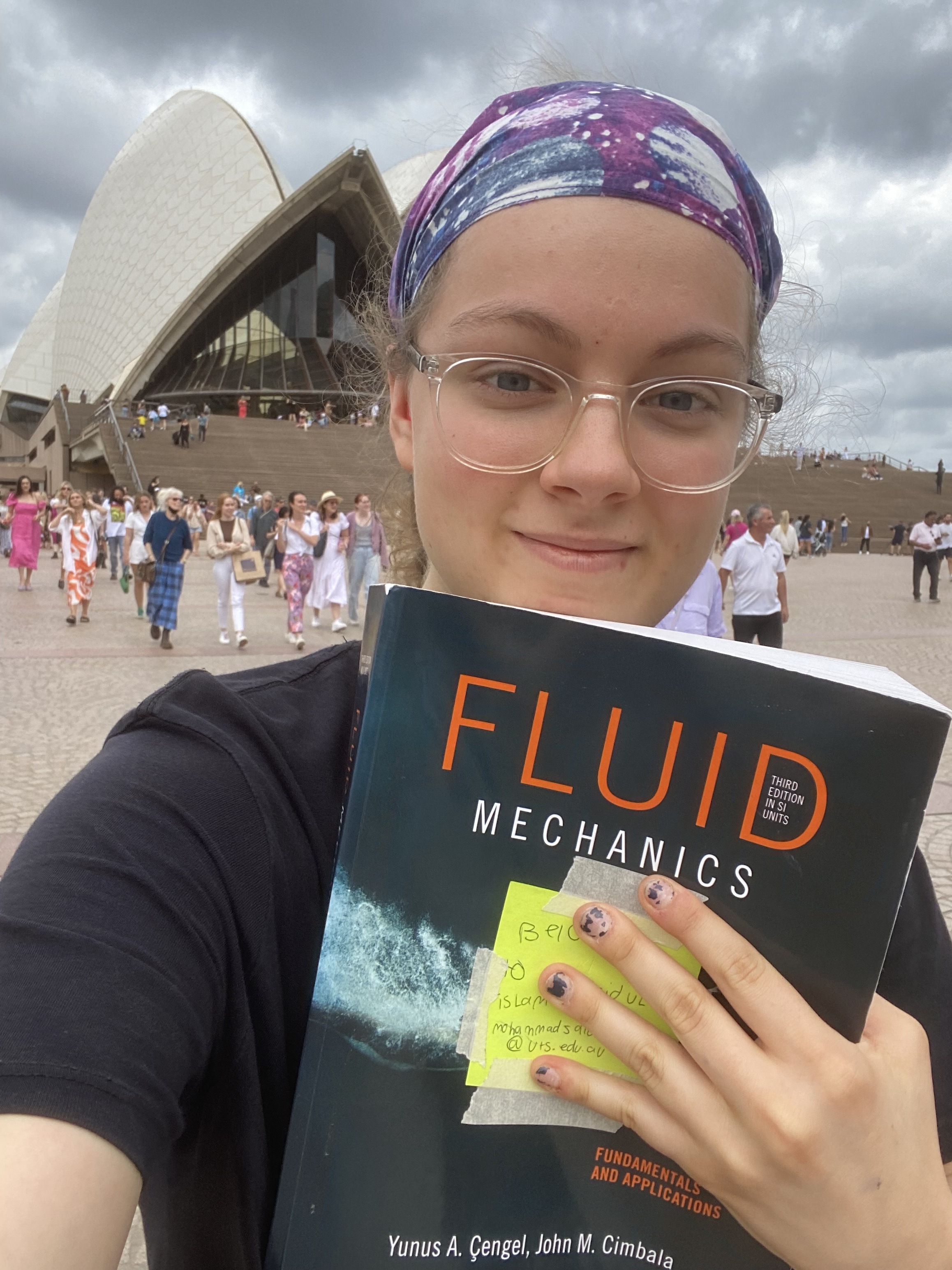 A selfie of Talita at the opera house. She is smiling and holding a textbook